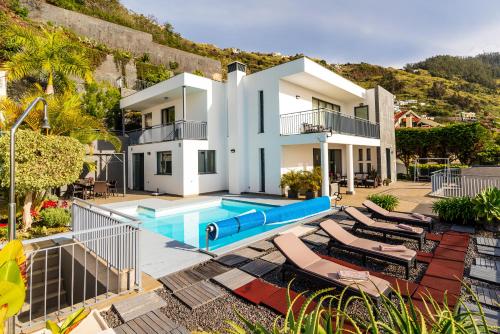 a villa with a swimming pool and lounge chairs at Villa Nunes, Big Holiday house with private pool in Calheta