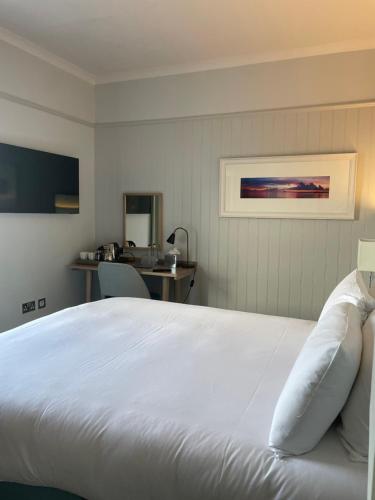 a bedroom with a large white bed and a desk at Trearddur Bay Hotel in Trearddur