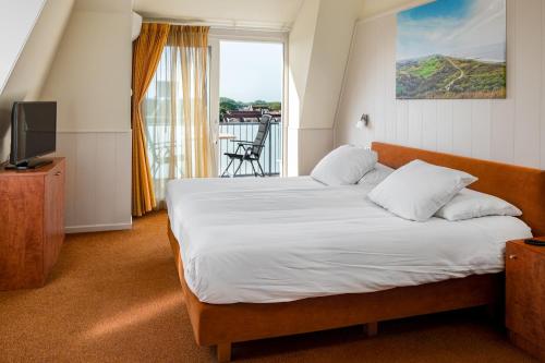 - une chambre avec un lit, une télévision et un balcon dans l'établissement Next Door, à Domburg