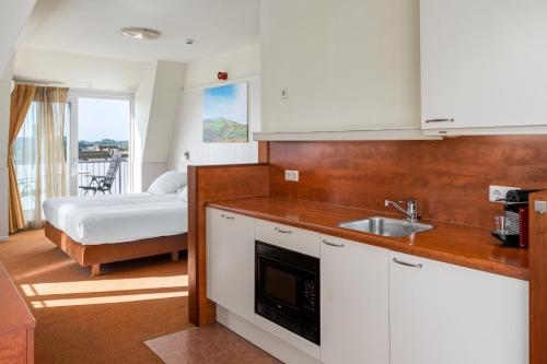 een keuken met een wastafel en een bed in een kamer bij Next Door in Domburg