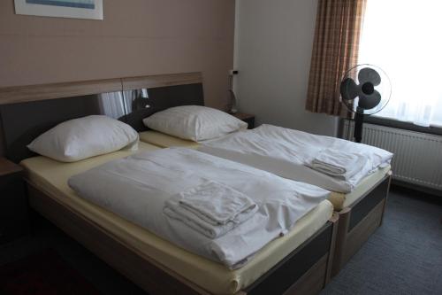 a bedroom with two beds with white sheets and pillows at Airport-Hotel zum Taubengrund in Kelsterbach