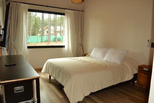 a bedroom with a large bed and a window at Chapelco Golf - Cabaña a Estrenar in San Martín de los Andes