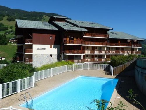 un hôtel avec une piscine devant un immeuble dans l'établissement Appartement rénové cosy avec piscine, pour 4 personnes, proche des pistes et du village. - FR-1-342-180, à Arêches