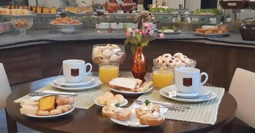 a table topped with cups of coffee and pastries at Hotel Jardim in Jardim
