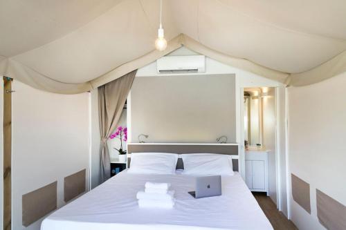 a bedroom with a white bed with a laptop on it at Firenze Certosa camping in Impruneta