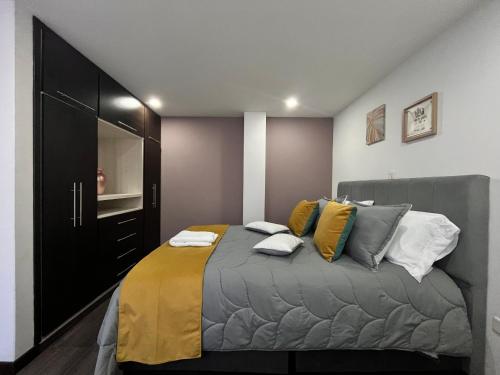 a bedroom with a bed with yellow and gray pillows at Confort 301 Apartamento Duitama in Duitama