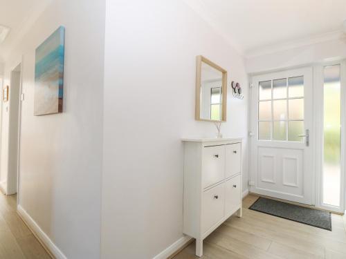 a white room with a dresser and a mirror at Glan Dwr in Pentraeth