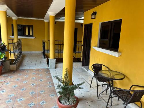 a yellow building with chairs and a table on a patio at Casa Alegria in Cobán