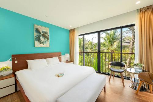 een slaapkamer met een groot wit bed en een tafel en stoel bij 4BR Villa Near The Beach & Shared Pool in Phu Quoc