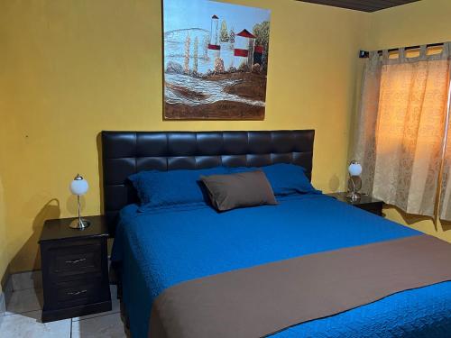 a bedroom with a blue bed and a painting on the wall at Casa Alegria in Cobán