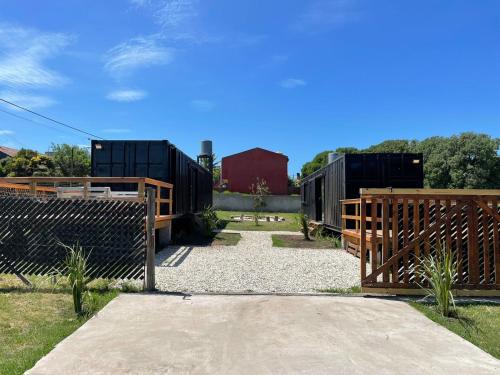 a wooden fence with a gate and a red barn at Apart Containers, Acantilados, unidad in Mar del Plata