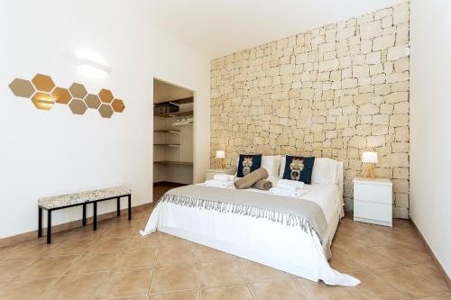 a bedroom with a large bed and a brick wall at Isula Relax - IsulaTravel in Modica