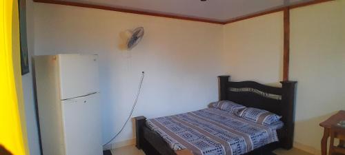 ein kleines Schlafzimmer mit einem Bett und einem Kühlschrank in der Unterkunft ALOHA BEACH FROM HOUSE in Parrita