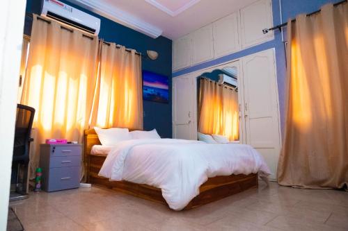 a bedroom with a large bed with blue walls and curtains at Studio cosy climatisé in Lomé