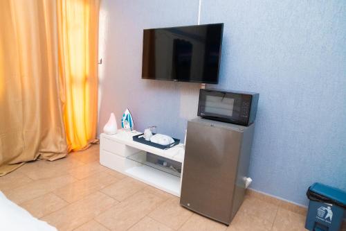 a room with a tv on a wall with a desk at Studio cosy climatisé in Lomé