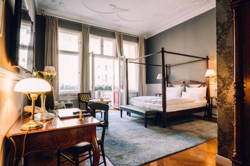 a bedroom with a four poster bed and a desk at HENRI Hotel Berlin Kurfürstendamm in Berlin