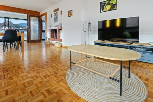 a living room with a table and a tv at Appartement au coeur du vignoble in Salgesch