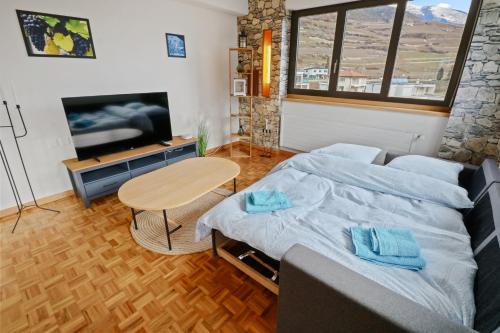 a bedroom with a bed and a table and a tv at Appartement au coeur du vignoble in Salgesch