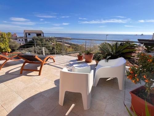 un patio con sillas blancas y vistas al océano en Sea House IUN Q7317, en Santa Maria Navarrese