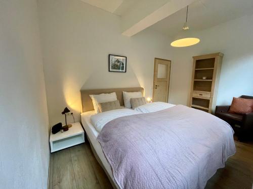 - une chambre avec un grand lit blanc et une chaise dans l'établissement Äuchen am Rosenthal, à Monschau