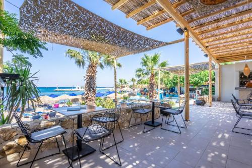 an outdoor patio with tables and chairs and the ocean at Lido Star in Faliraki