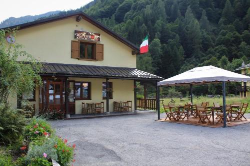 Rifugio Alpenrose في Carcoforo: مبنى امامه طاولات وكراسي