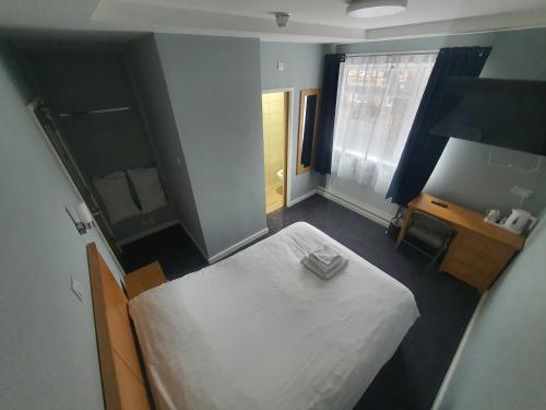 een slaapkamer met een wit bed en een spiegel bij Newark Hotel Peterborough in Peterborough