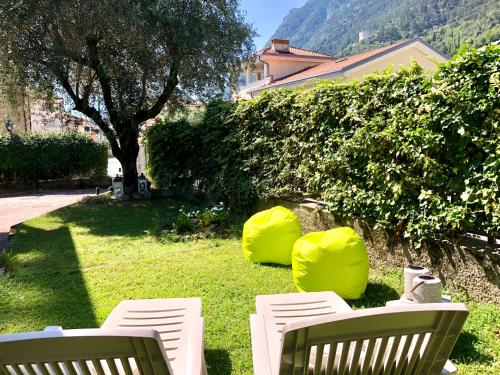 two white chairs sitting on a lawn with a tree at Appartamento villatorretta24 in Riva del Garda