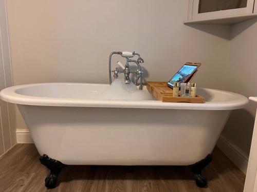 a white bath tub with a tablet on top of it at No2 Clarence grade II Regency townhouse short walk to racecourse and town centre in Cheltenham