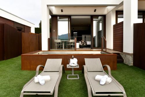 two chairs on a lawn with a hot tub at Suites Natura Mas Tapiolas in Santa Cristina d'Aro