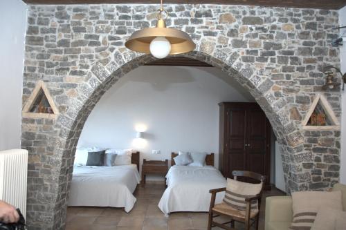 a room with two beds and a stone wall at Αργουλιάς in Tzermiádon