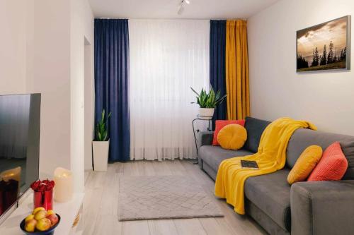 a living room with a gray couch with a yellow blanket at Apartament Pod Jedynką in Bielsko-Biała