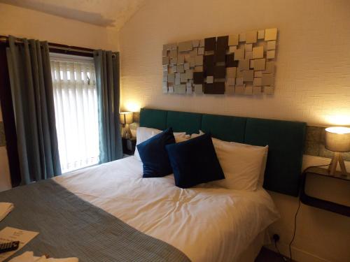 a bedroom with a bed with white sheets and blue pillows at The Rockley Hotel in Blackpool