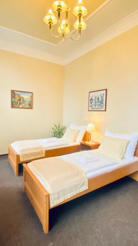 two beds in a room with a chandelier at Penzion Černý Kůň in Hradec Králové