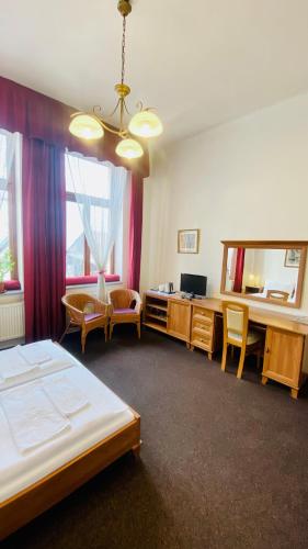 a bedroom with a bed and a desk and a mirror at Penzion Černý Kůň in Hradec Králové