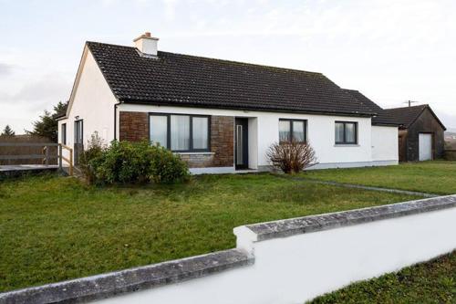 a white house with a green yard at Doolin Getaway. in Lisdoonvarna