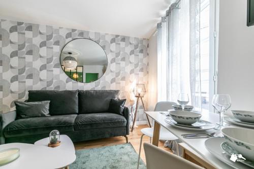 MBA Splendide Appart - Wilson 1 - Mairie de Montreuil في مونتروي: غرفة معيشة مع أريكة خضراء ومرآة