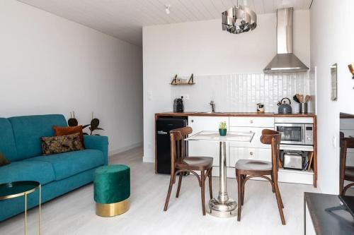 a living room with a blue couch and a kitchen at La Javanaise in Narbonne-Plage