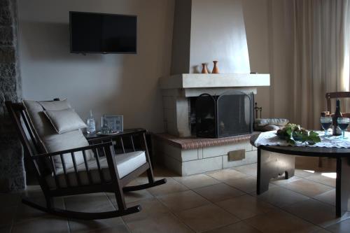 a living room with a fireplace and a chair and a table at Αργουλιάς in Tzermiádon