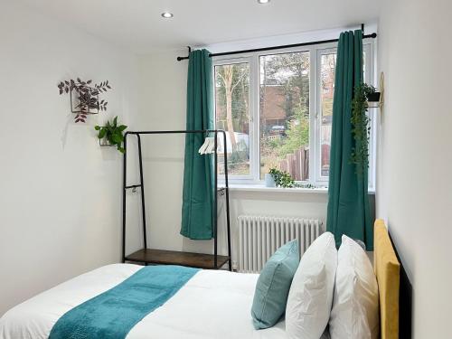 a bedroom with a bed with green curtains and a window at Perfect Stay For Family & Contractors With Free Parking in Luton