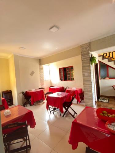 um restaurante com mesas vermelhas e cadeiras num quarto em Pousada Véu de Noiva em São Tomé das Letras