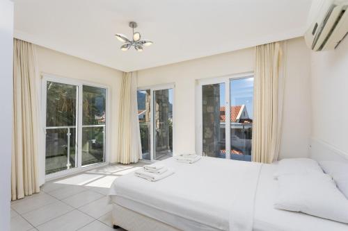 Schlafzimmer mit einem weißen Bett und großen Fenstern in der Unterkunft Golden Heights 5 in Oludeniz
