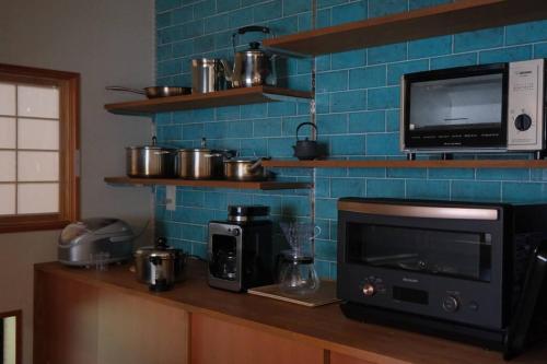 a kitchen with a counter with a microwave and a tv at ワタリグラスハウス in Gamō