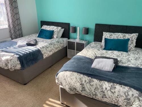twee bedden in een slaapkamer met blauwe muren bij Howard’s House, Home from Home in Thornaby on Tees