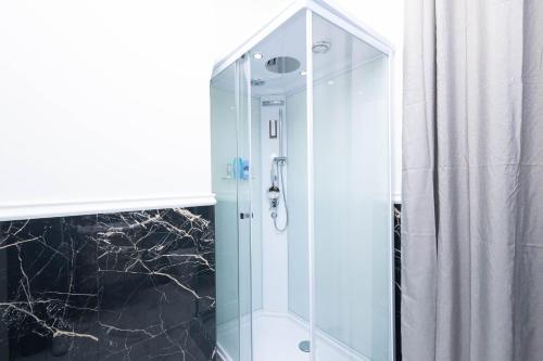 La salle de bains est pourvue d'une douche avec une porte en verre. dans l'établissement CF Luxury House, à Lido di Ostia