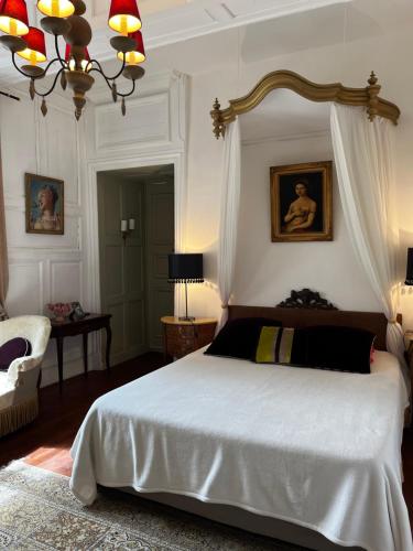- une chambre avec un grand lit blanc et une chaise dans l'établissement Le Logis de Saint Cyr, à Issoudun