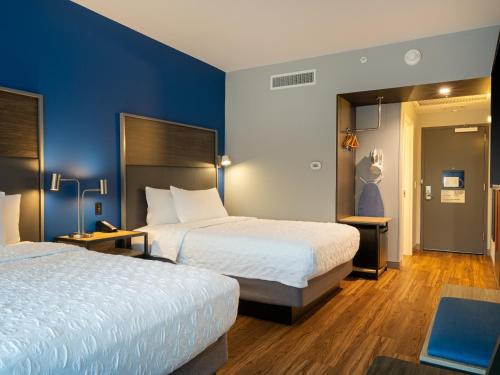 two beds in a hotel room with blue walls at Tru By Hilton Atlanta Airport College Park in Atlanta