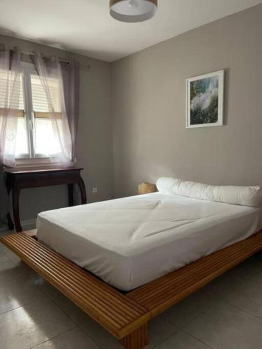 - un lit avec un cadre en bois dans une chambre dans l'établissement La villa les parfums d’Ete, à Ornaisons