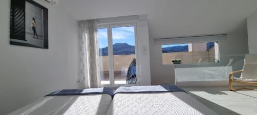 a white bedroom with a bed and a window at Apartamentos Miradores del Isasa in Herce