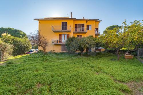 a yellow house on top of a green hill at Appartamenti La Marina - Goelba in Marciana Marina
